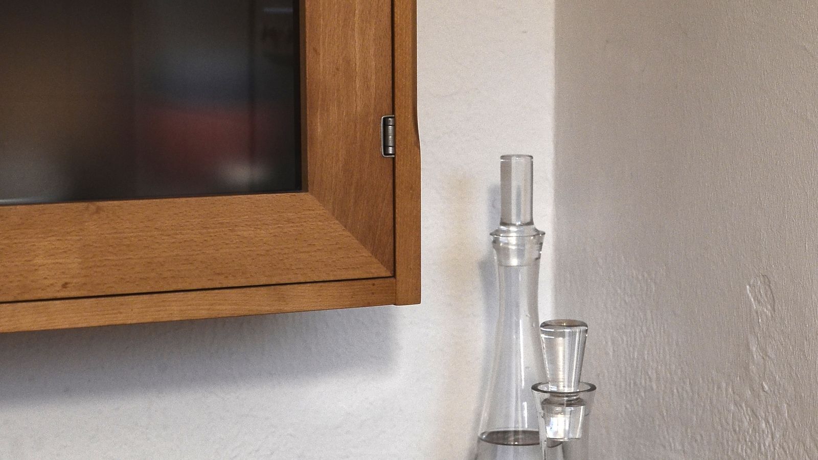 Glass bottles and small kitchen items arranged on a wooden countertop near a corner