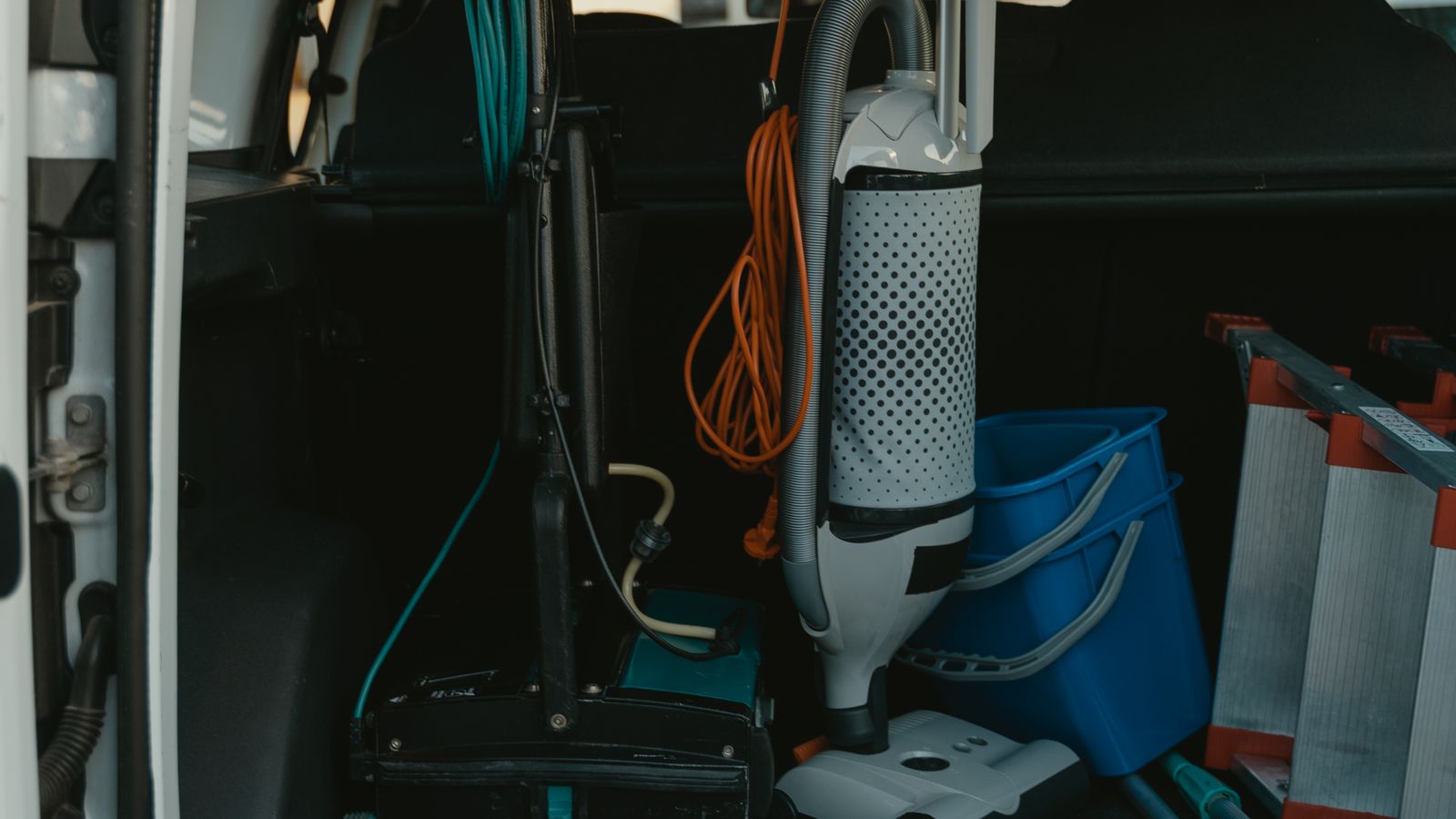 Cordless electric broom leaning against a kitchen counter on a hardwood floor