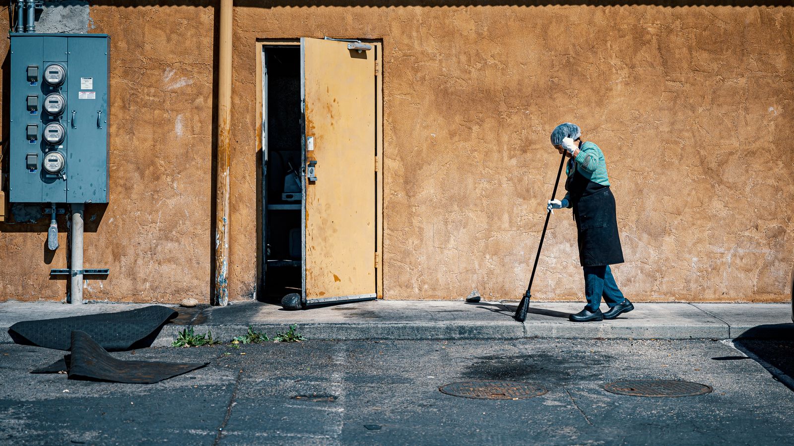 Person using a lightweight electric broom to sweep crumbs from a tile kitchen floor