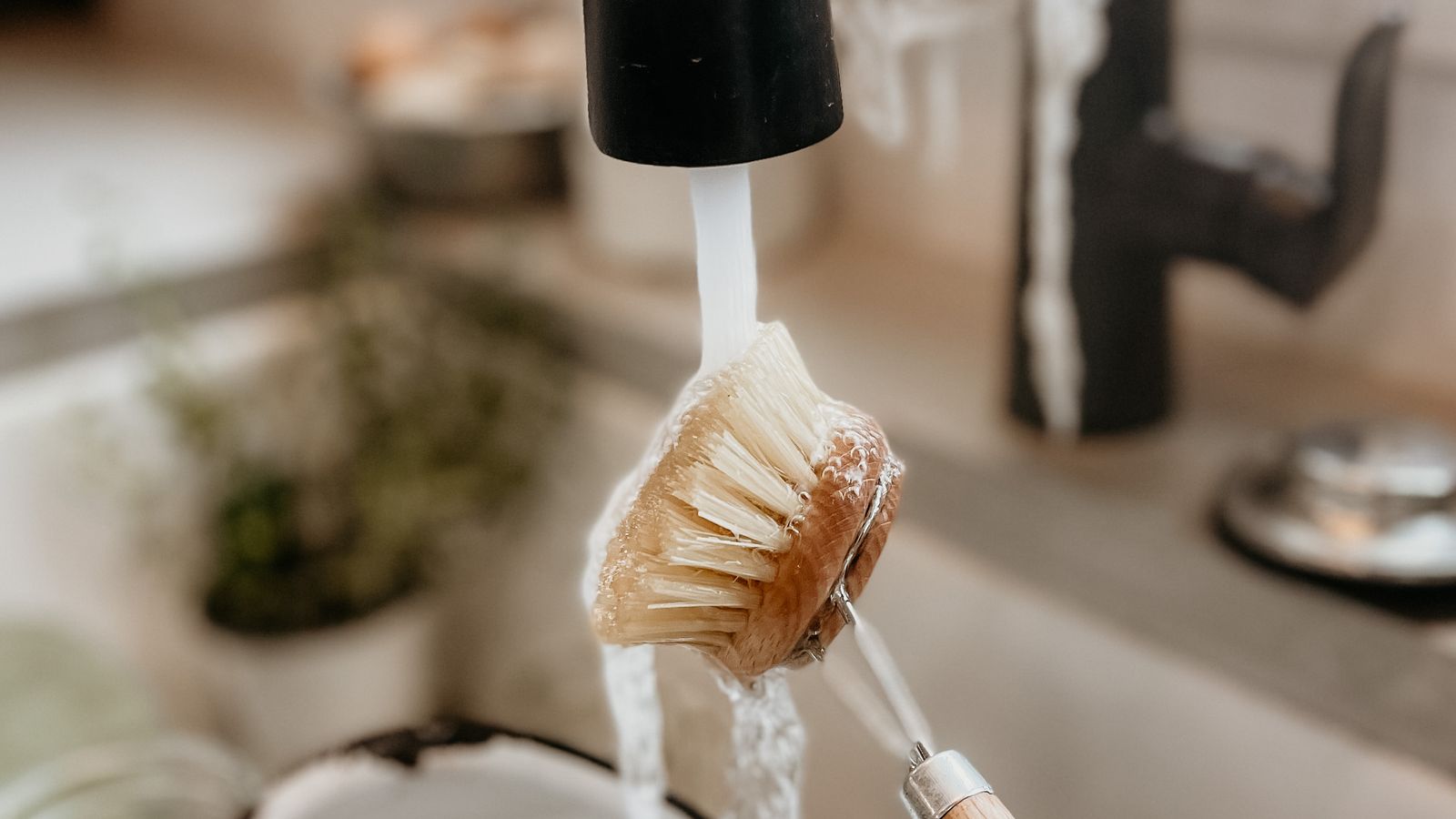 Dish brush and cleaning cloth beside a kitchen sink for daily dishwashing