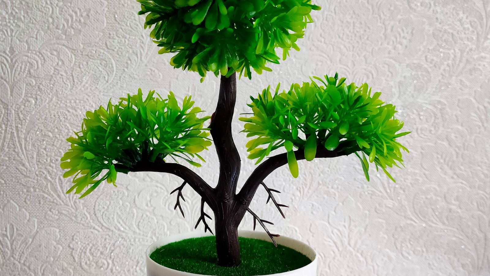 Realistic artificial plant in a ceramic pot styled next to home decor