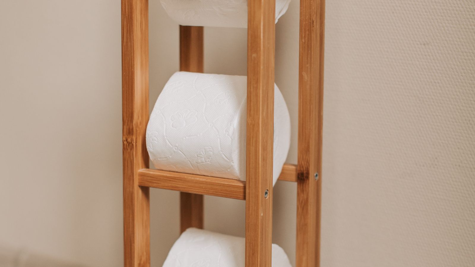 Wooden paper towel roll stand with rolls stacked beside it