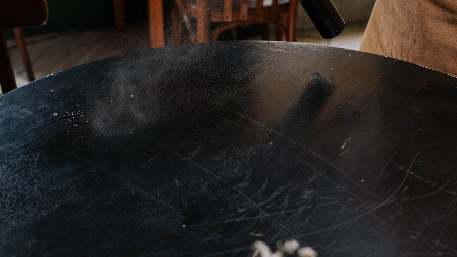 Person spraying fabric refresher on upholstery to remove odors
