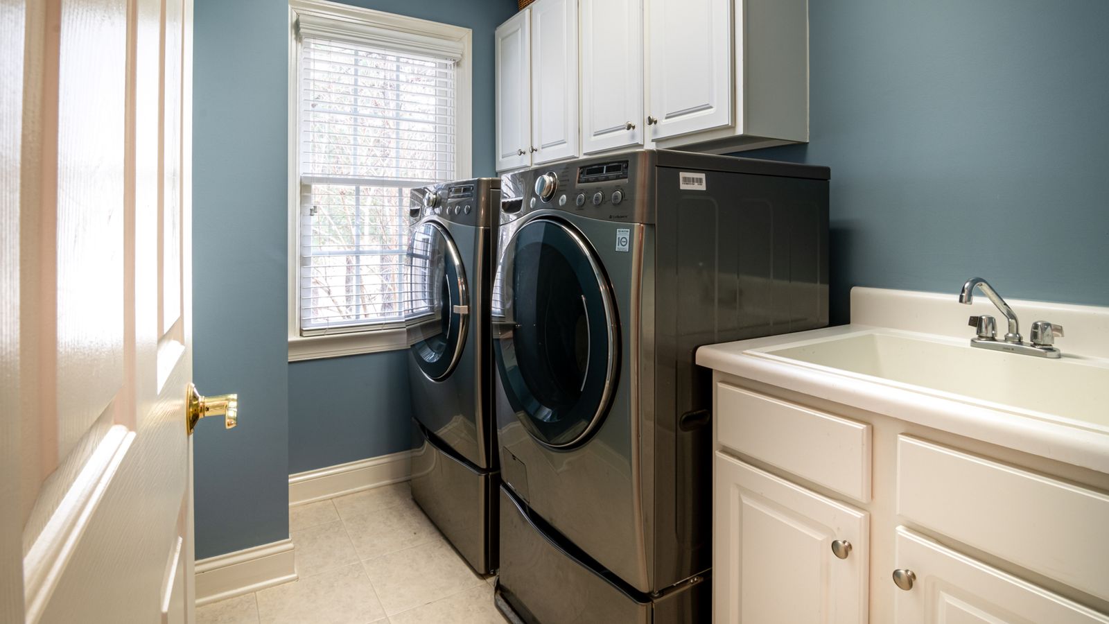 Organized laundry room with washer, dryer, and a rug on the floor between them