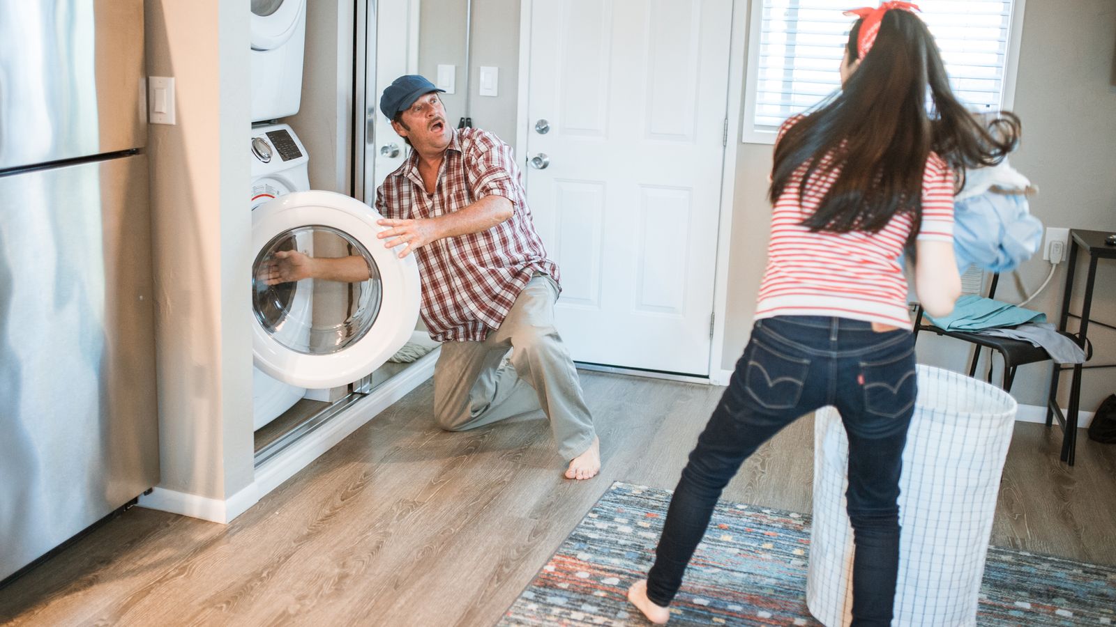 Close-up of a person loading wet laundry into a front-load washing machine near a floor rug