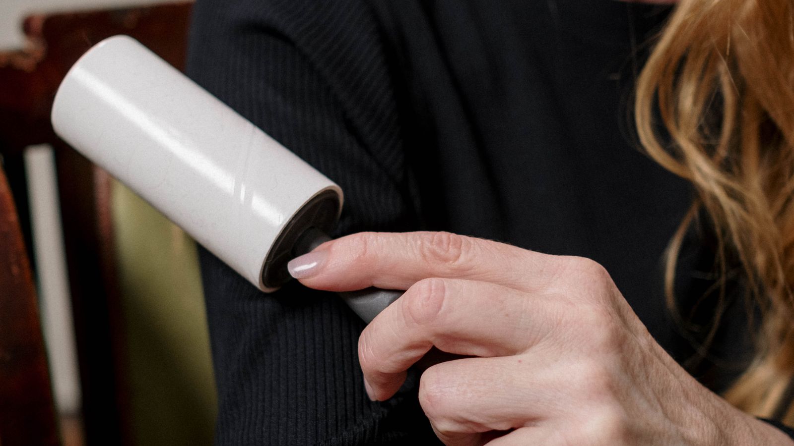Close-up of a hand applying stain remover spray directly onto a fabric stain