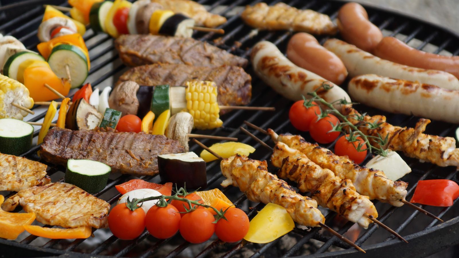 Assorted vegetables and meat grilling on a charcoal barbecue