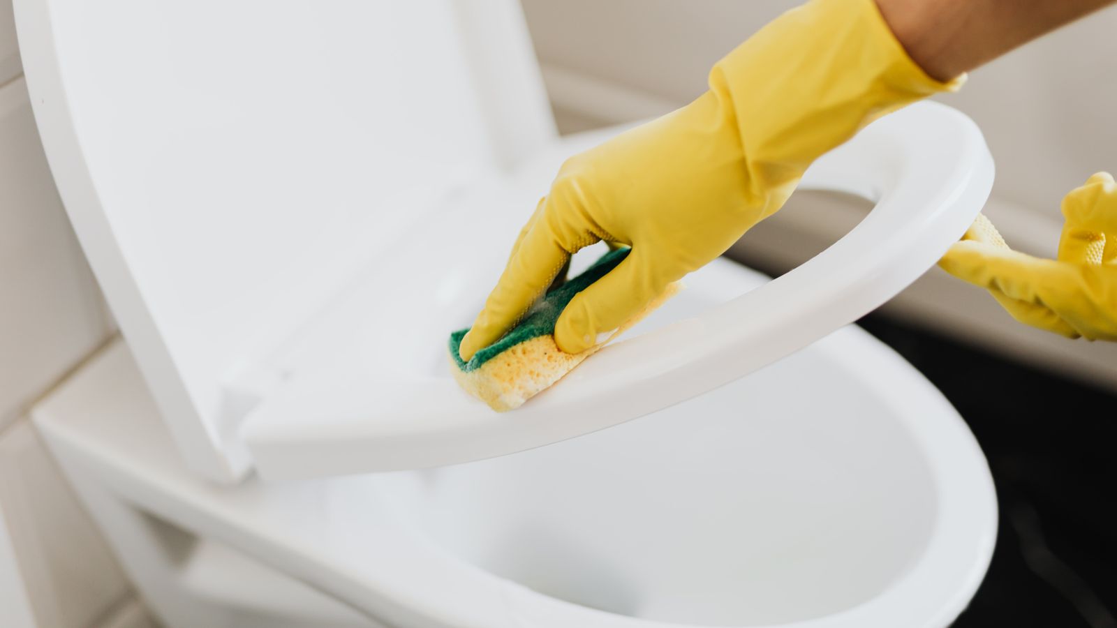 Bathroom cleaning supplies including gloves and spray bottles arranged for toilet maintenance