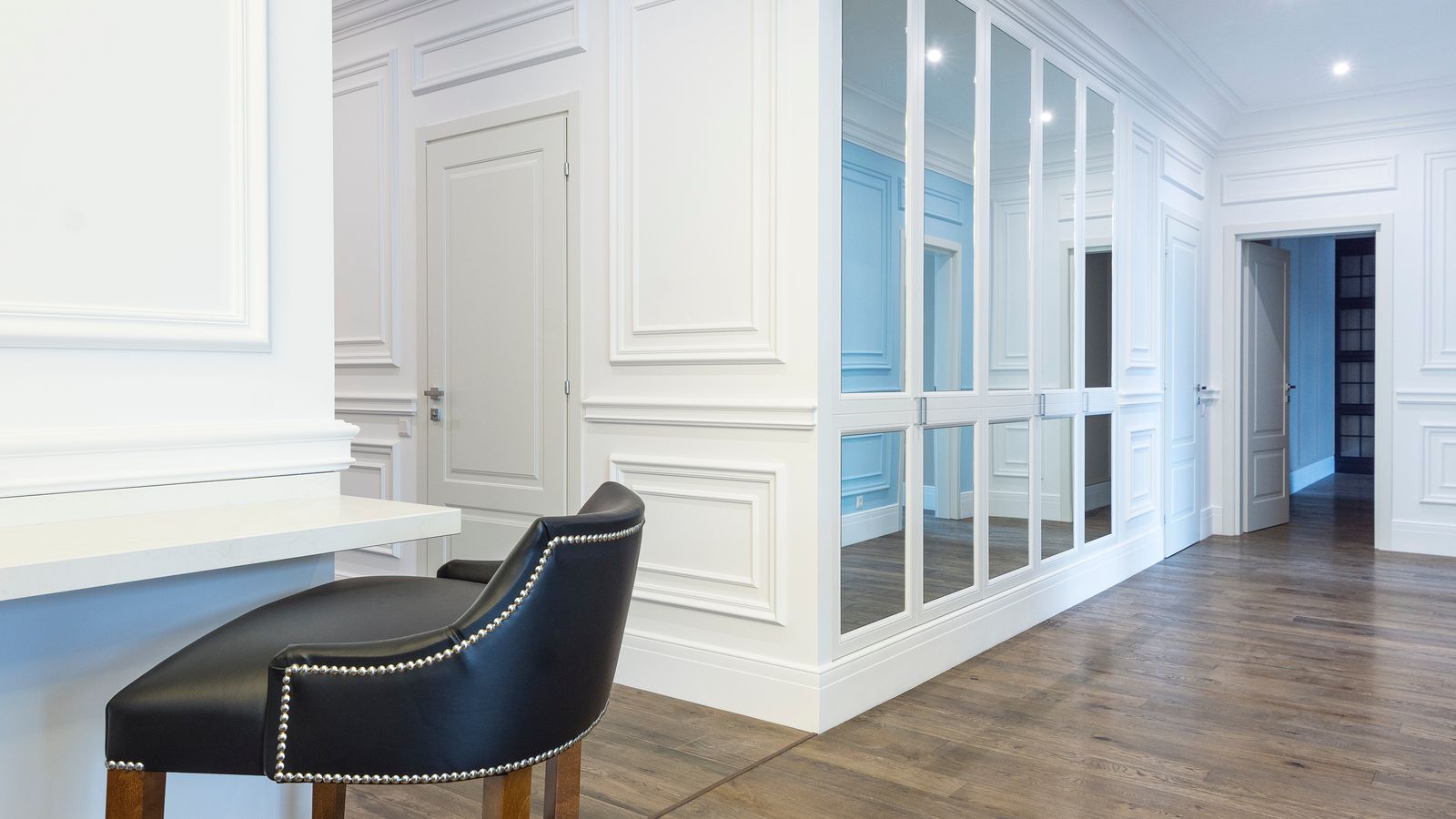 Modern wall mirror with metal frame reflecting a well-lit bedroom