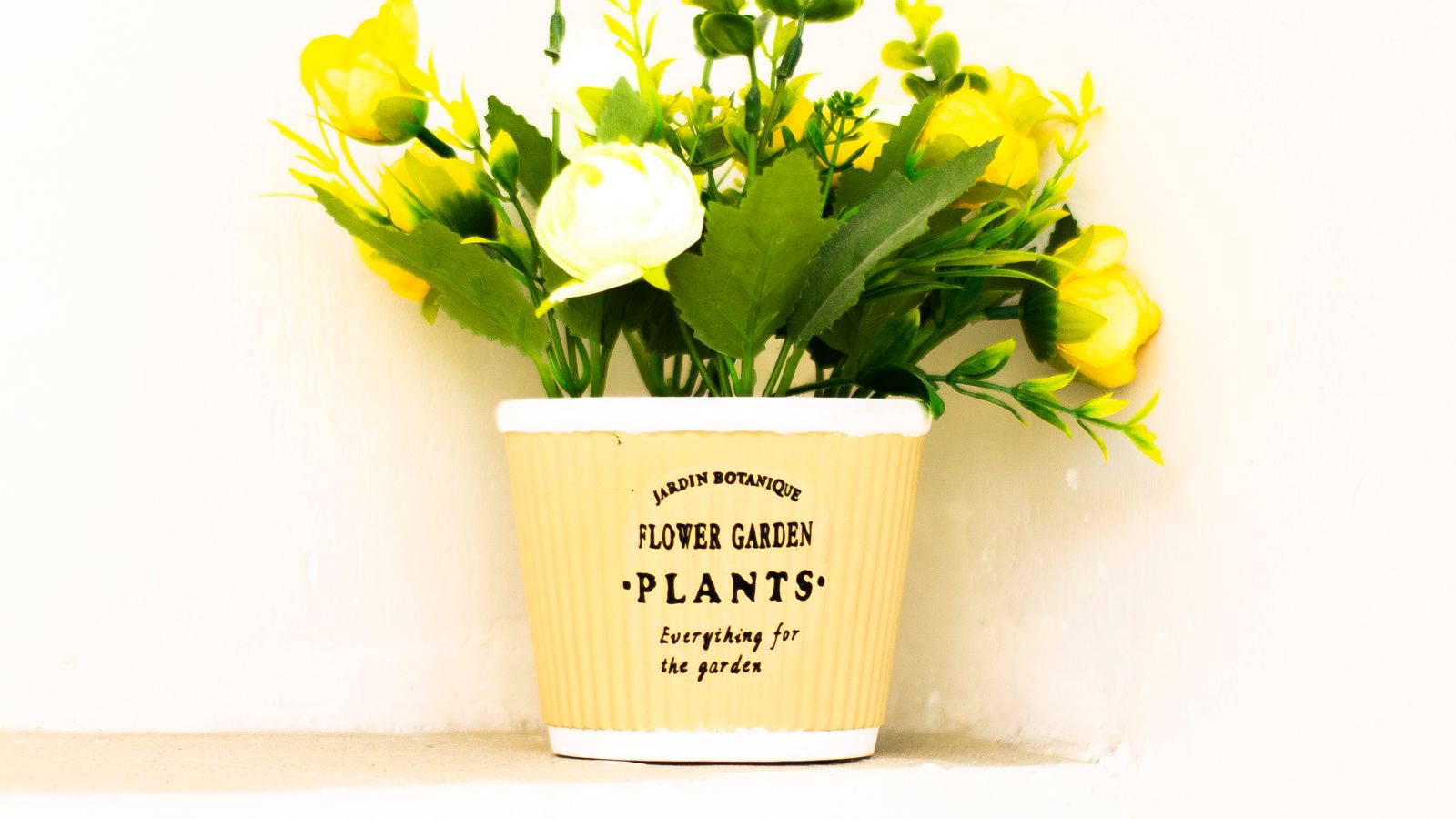 Faux flower arrangement in a ceramic vase styled next to home decor accents