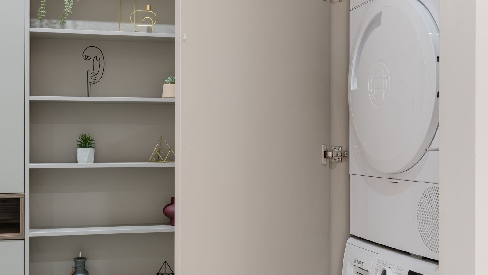 Wall-mounted shelf above a washing machine holding folded laundry and storage baskets