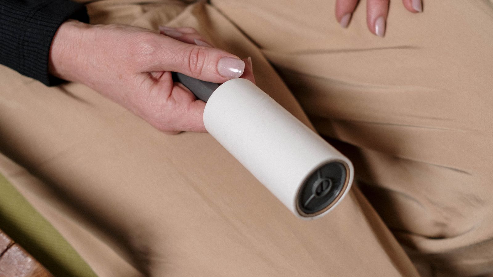 Person removing pet fur and lint from fabric pants with a handheld tool