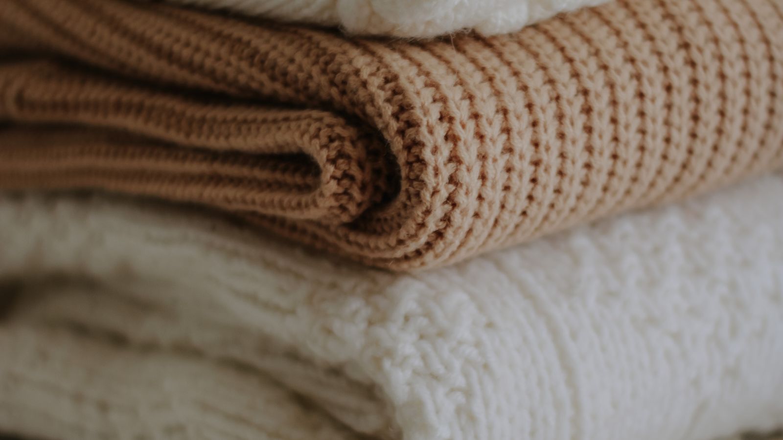 Close-up of folded knitted wool sweaters showing fabric texture and pilling