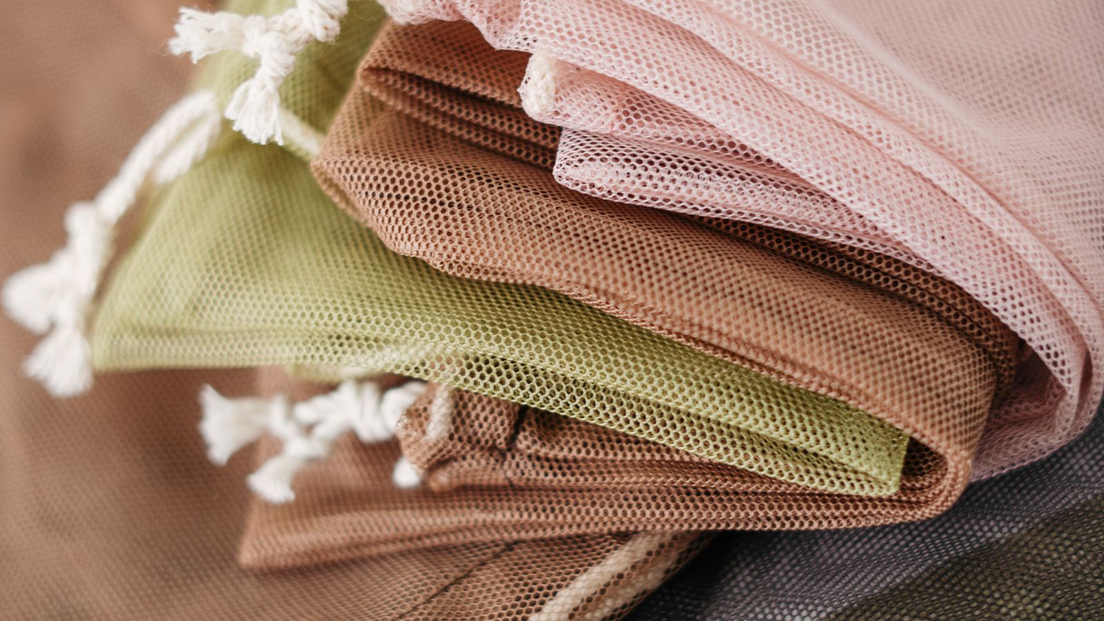Stack of colorful reusable mesh laundry bags ready for use