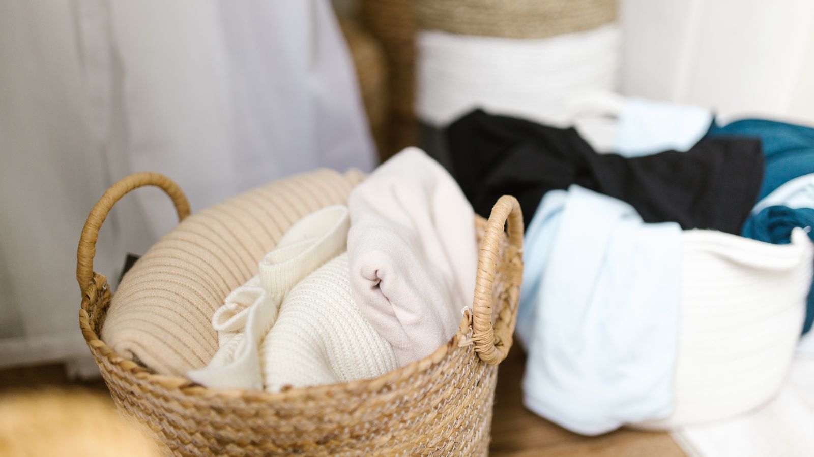 Clothes neatly organized in woven storage baskets in a laundry room
