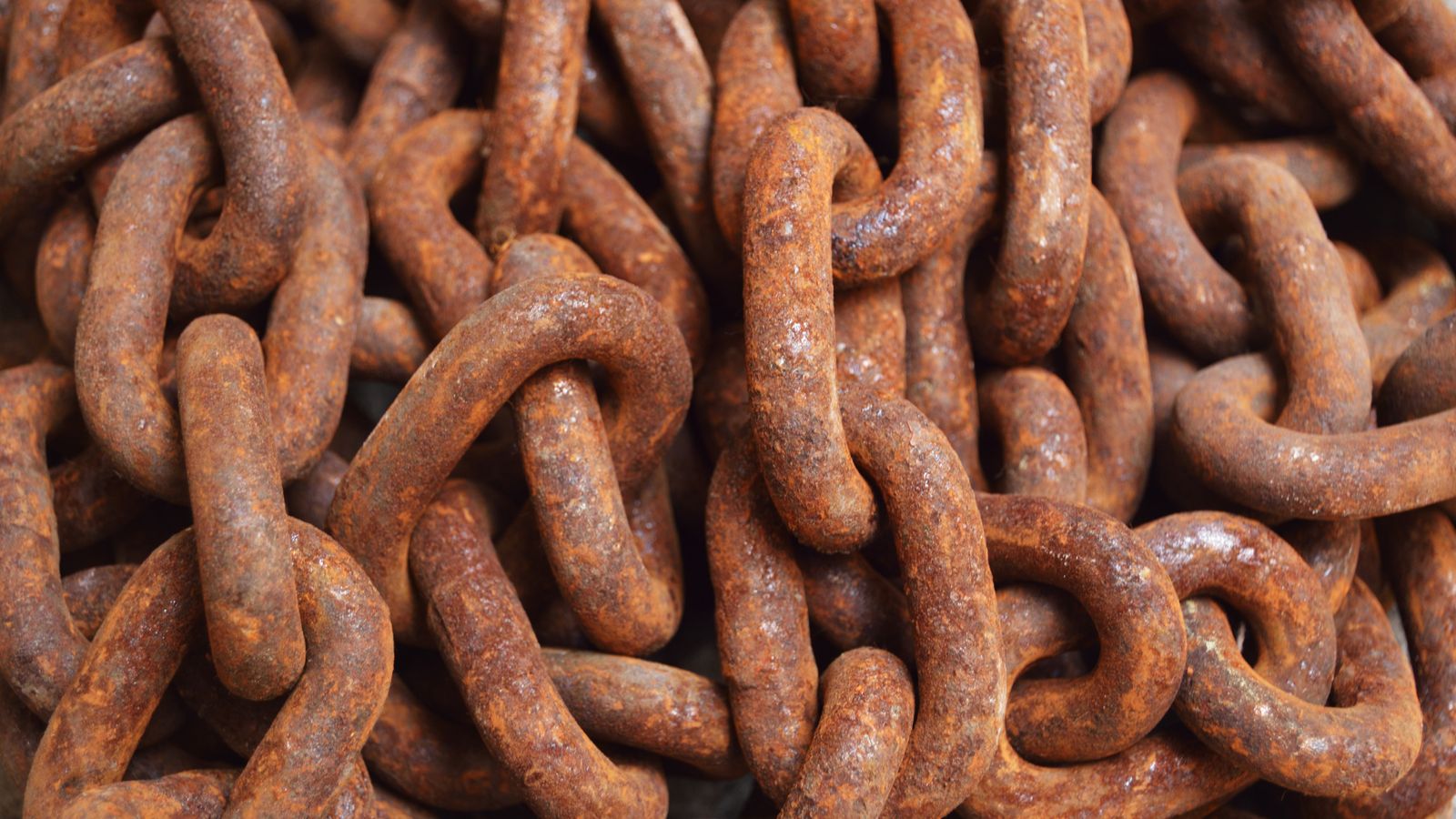 Rusty metal chain and tools being treated during a rust removal process