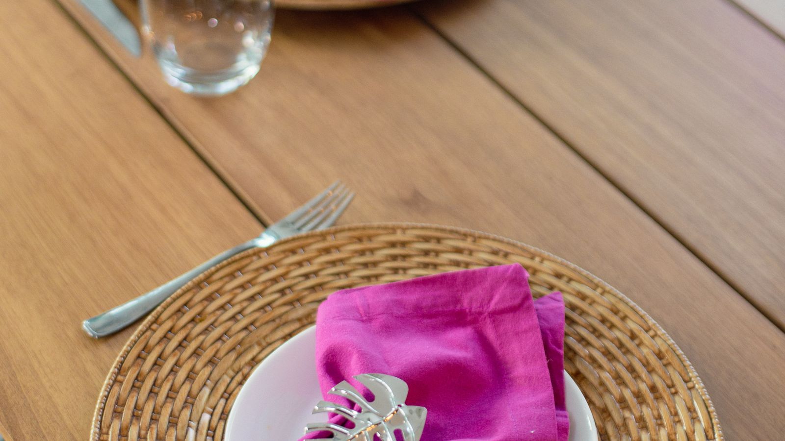 Table set with woven placemats and folded napkins secured with decorative rings