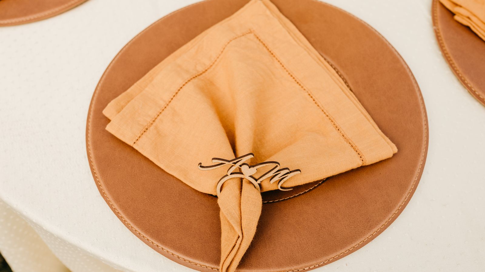 Close-up of a folded napkin held together by a decorative napkin ring on a wooden plate