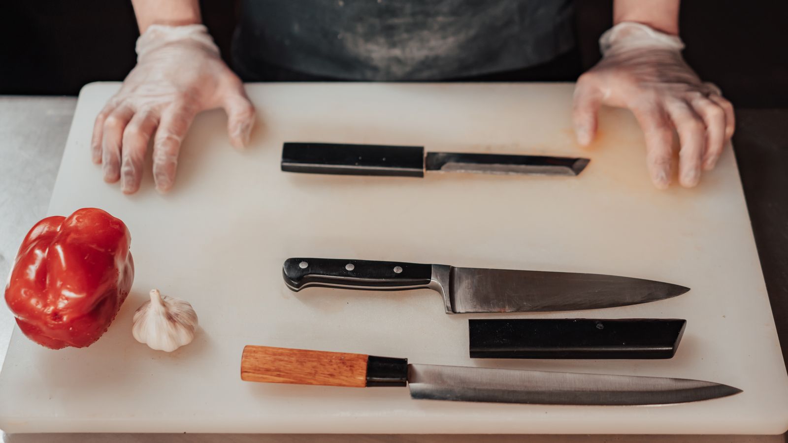 Clean knives laid out on a cutting board next to a wooden storage block