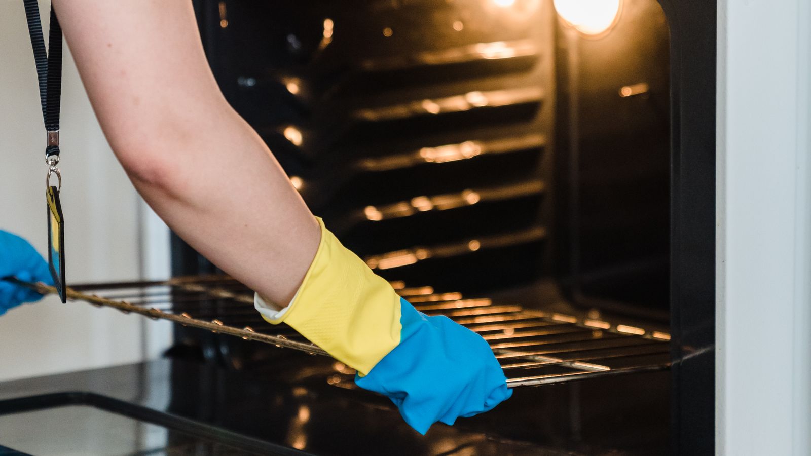 Person wiping down a stainless steel range cooktop with a cleaning cloth