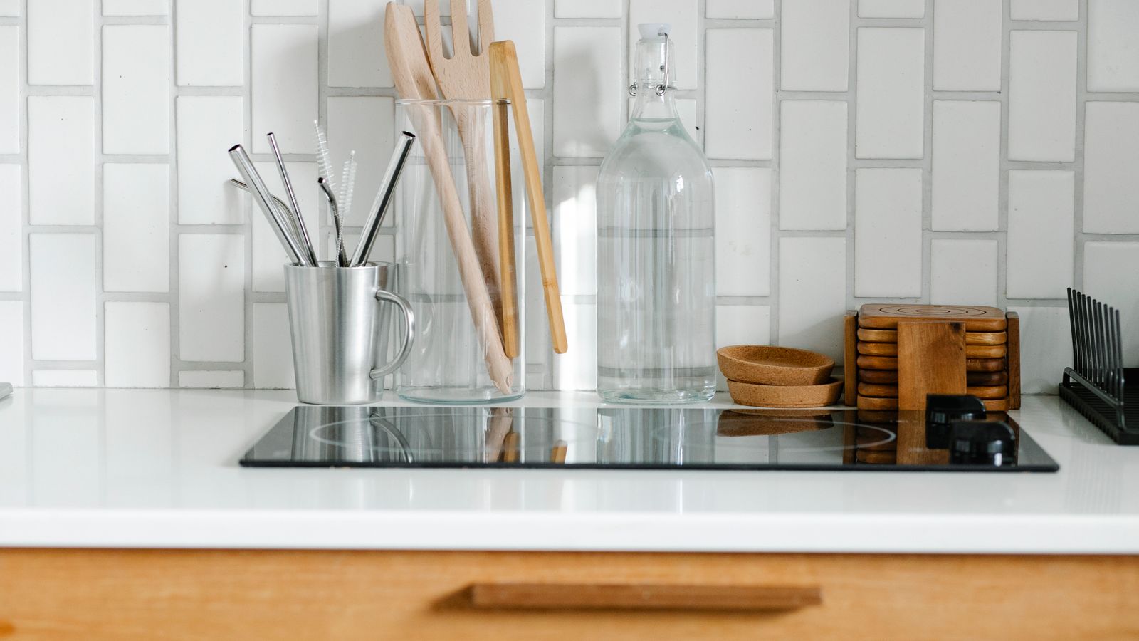 Small kitchen counter corner with utensils, glass bottles, and grains stored in jars