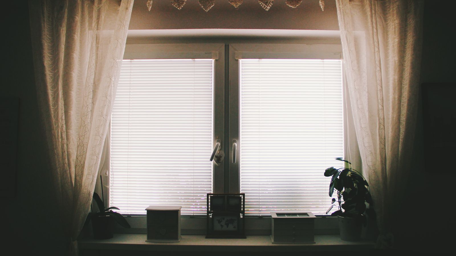Kitchen window dressed with a short cafe curtain covering the lower half for privacy