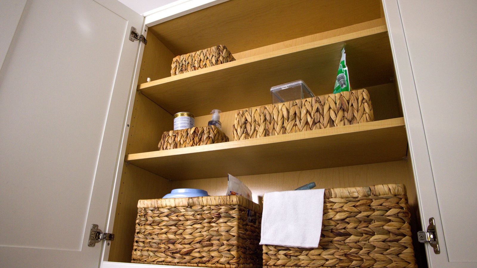 Neatly organized kitchen storage cabinet using labeled baskets and bins
