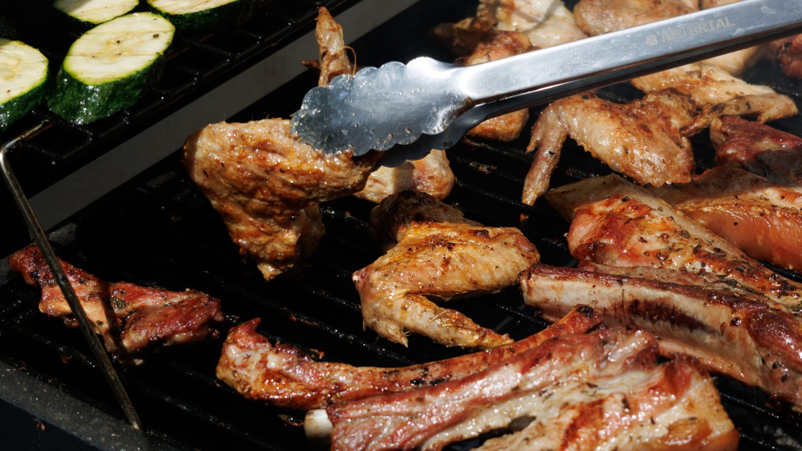 Pellet grill smoker sitting on a backyard patio with smoke rising from the hopper