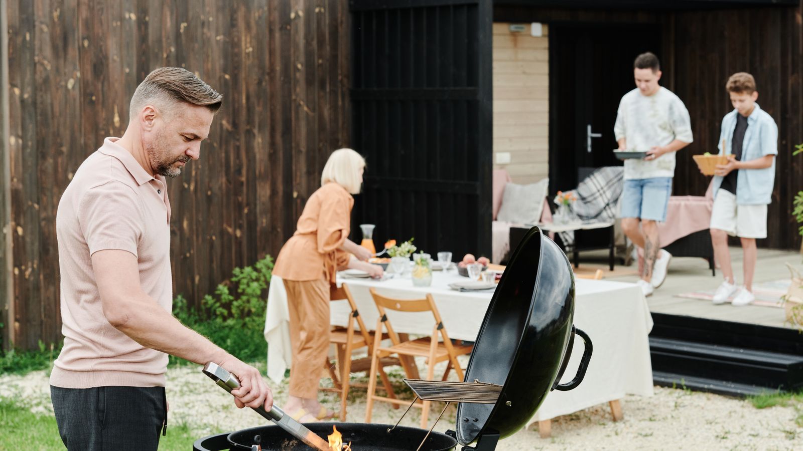 Close-up of a person scraping grease and ash residue from a grill grate