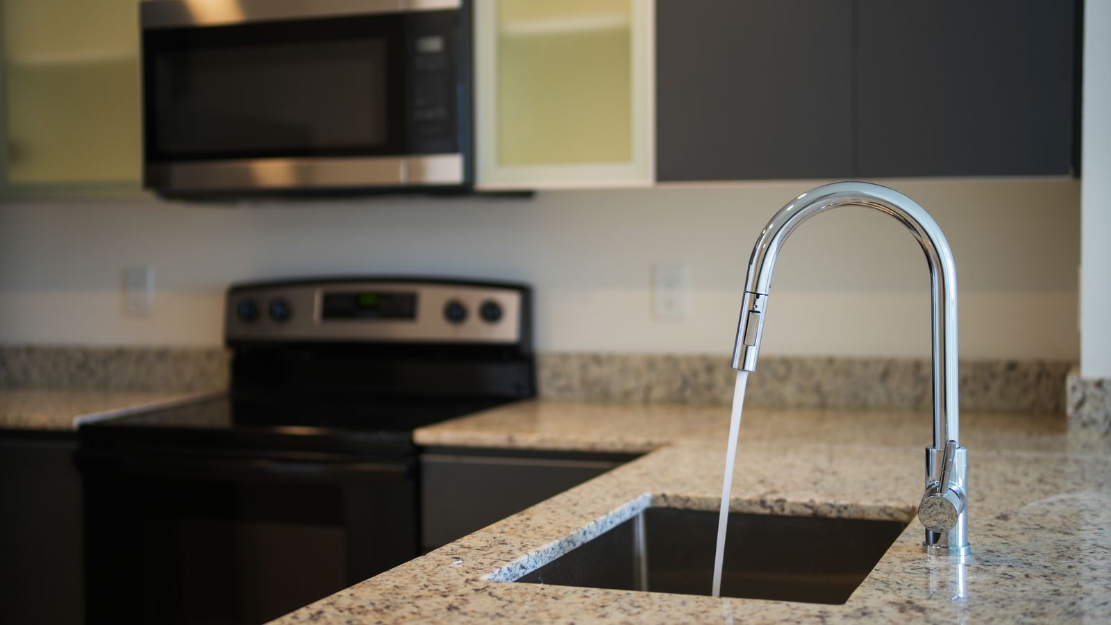 Close-up of a pot filler faucet swing arm joint above a granite countertop