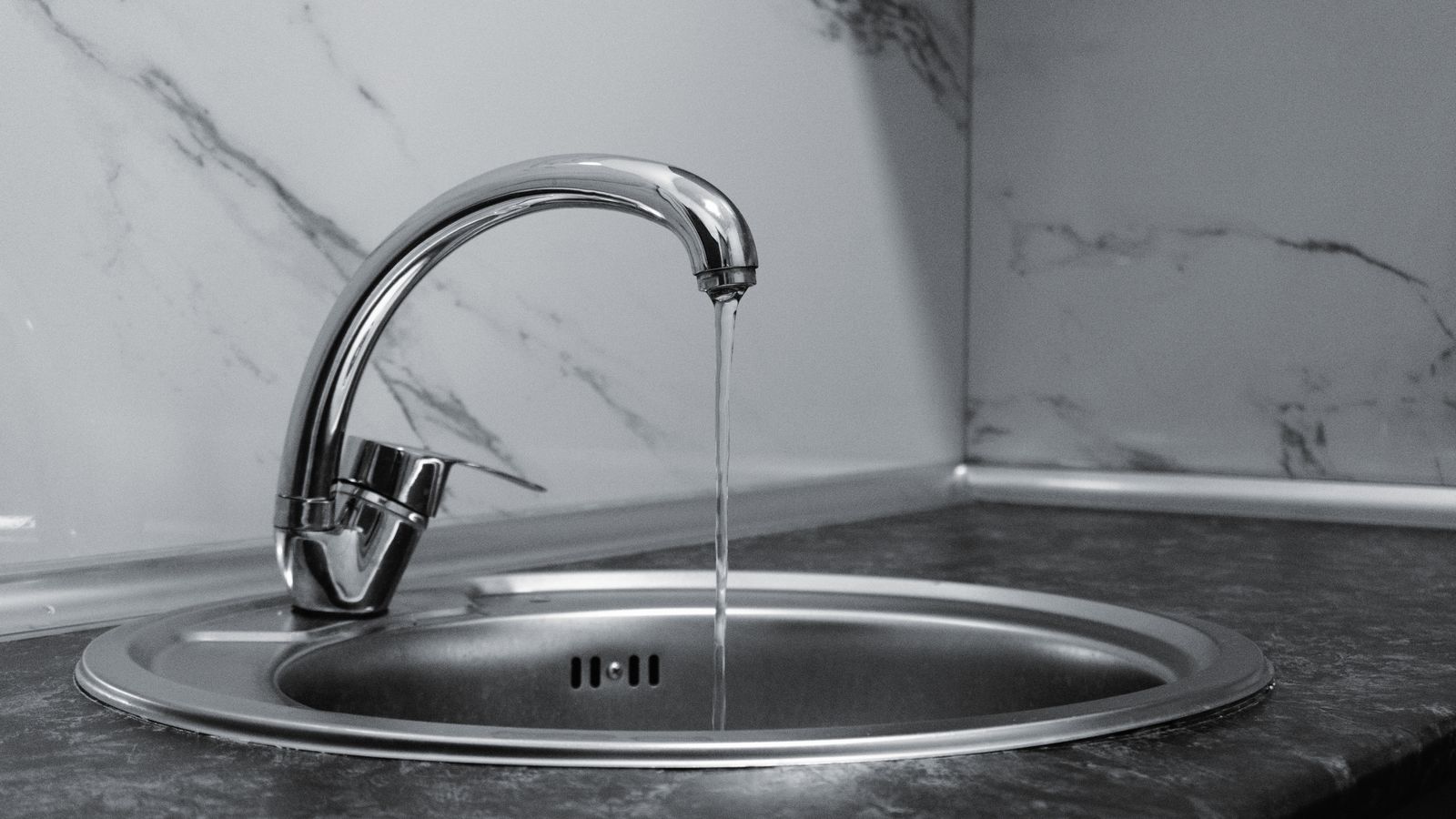 Modern chrome kitchen faucet with running water demonstrating proper water flow