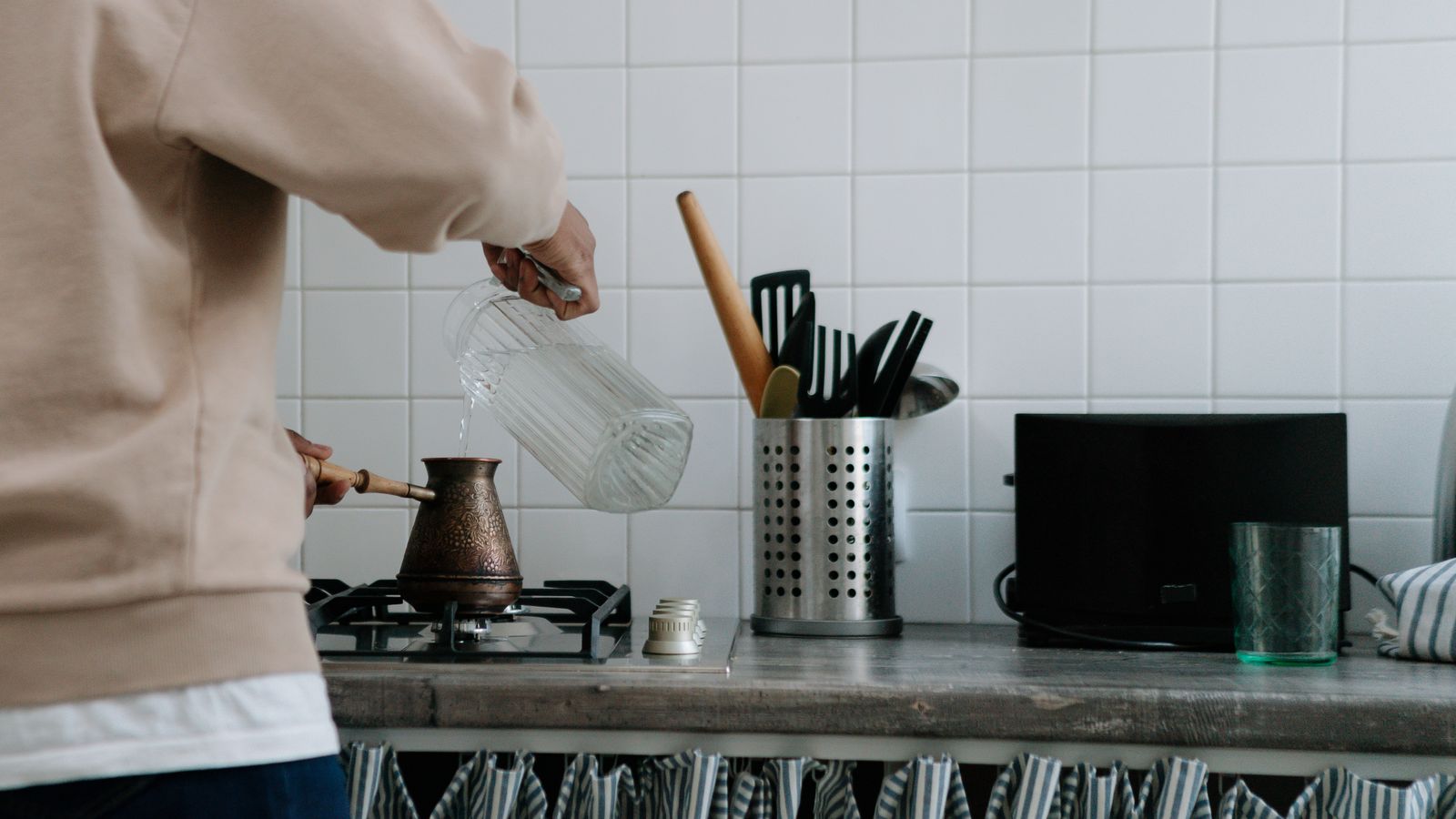 Slow cooker with stainless steel finish sitting on a kitchen counter near cooking ingredients