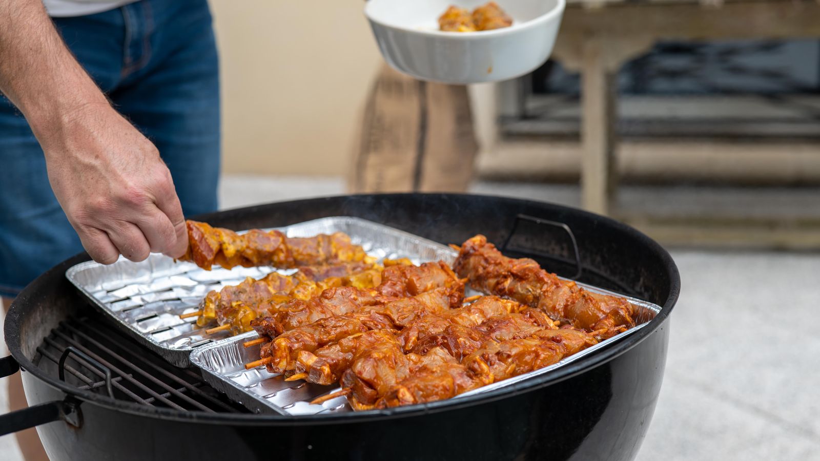 Skewers grilling alongside a flat-top griddle at an outdoor cooking station