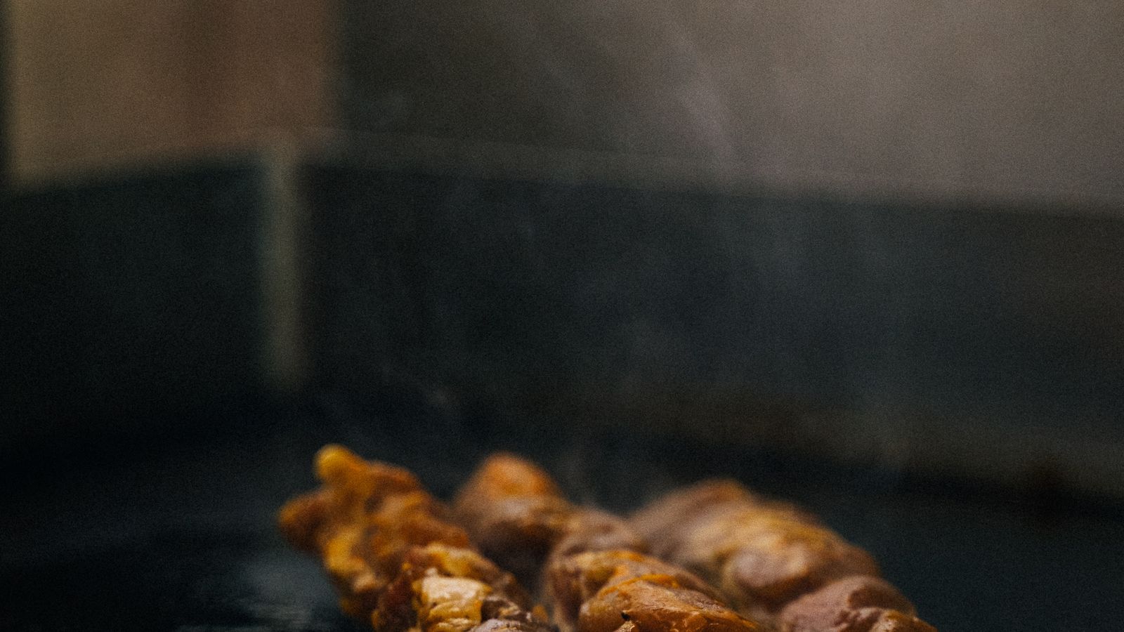 Close-up of a cast iron press searing meat on a flat-top griddle