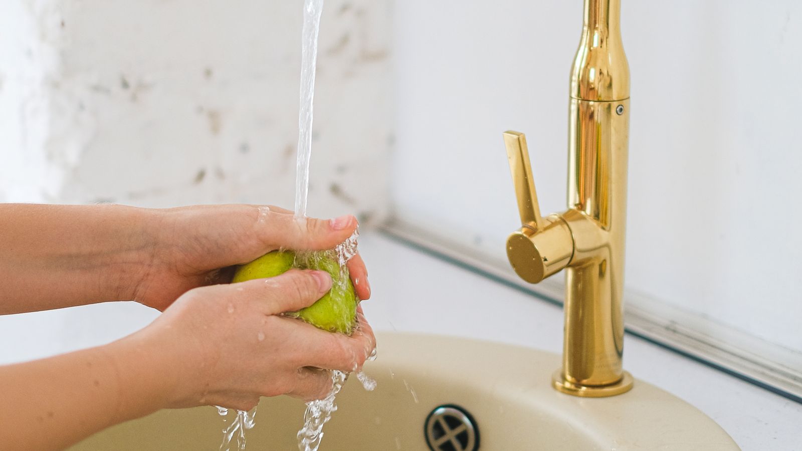 Touchless kitchen faucet with sensor activation dispensing water into a sink