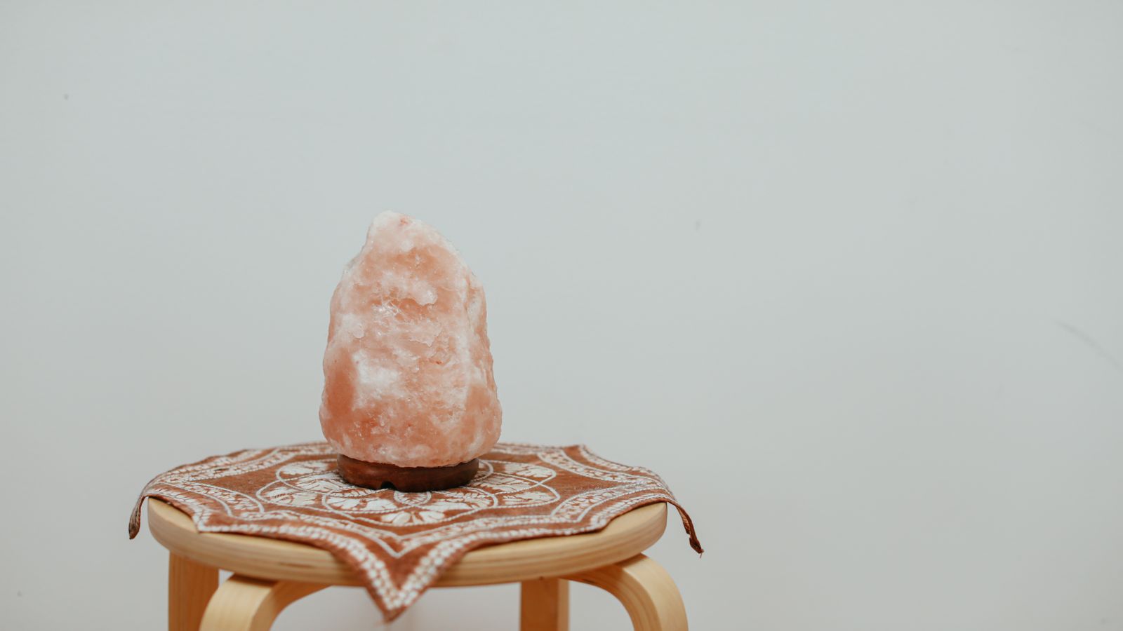 Himalayan salt lamp glowing warmly on a wooden side table in a cozy bedroom