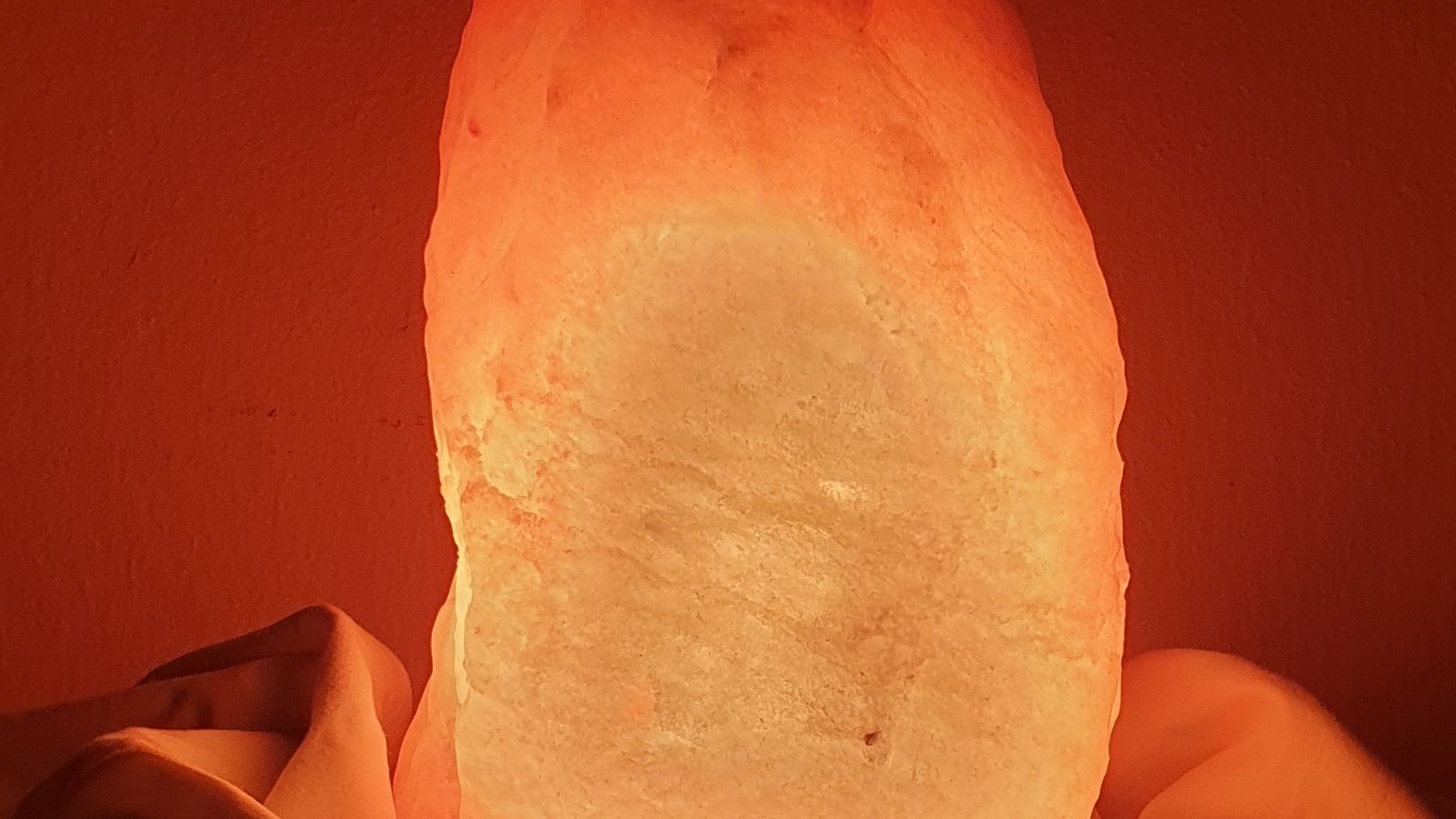 Close-up of an illuminated Himalayan salt lamp beside a nightstand at night