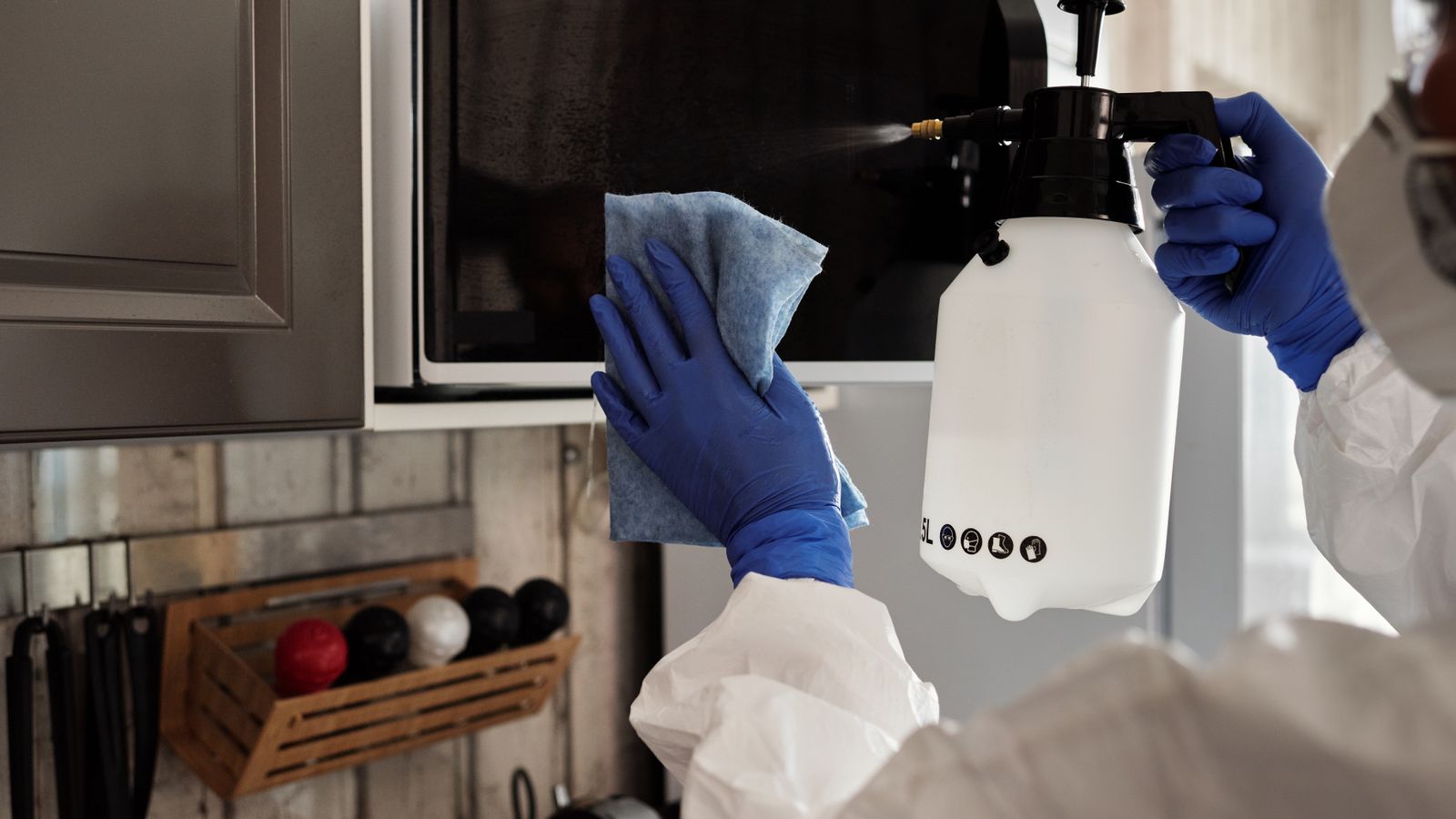 Person wiping down the inside of a microwave with a cleaning wipe
