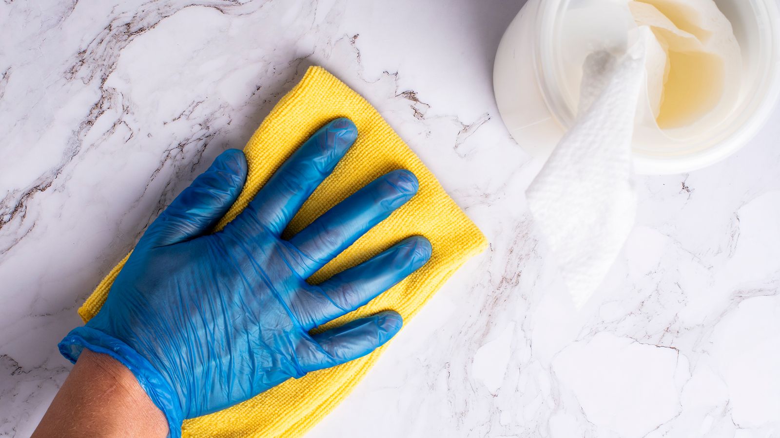 Gloved hand holding a disinfectant wipe over a countertop