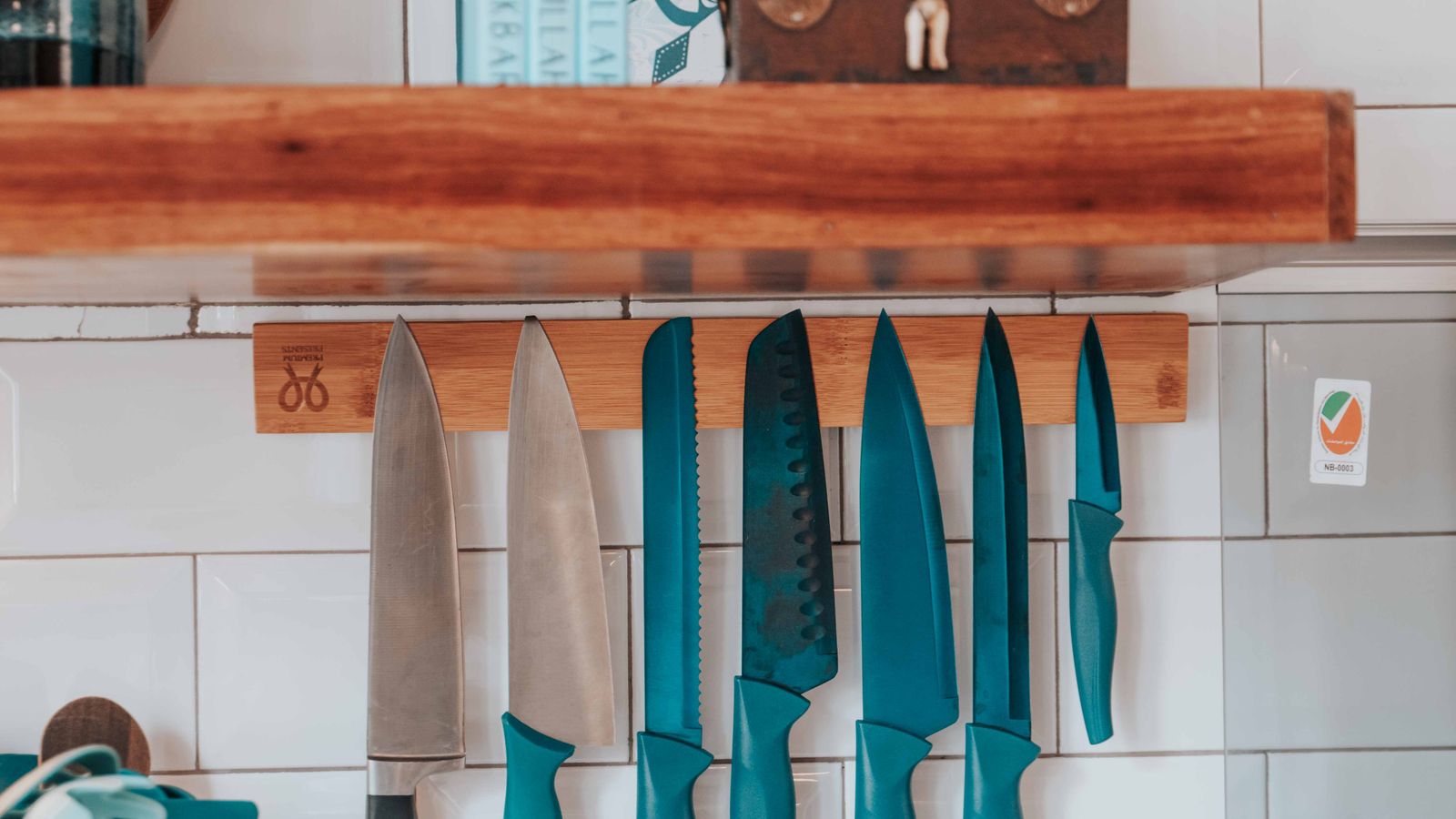 Kitchen knives hanging blade-up on a magnetic strip mounted under a cabinet