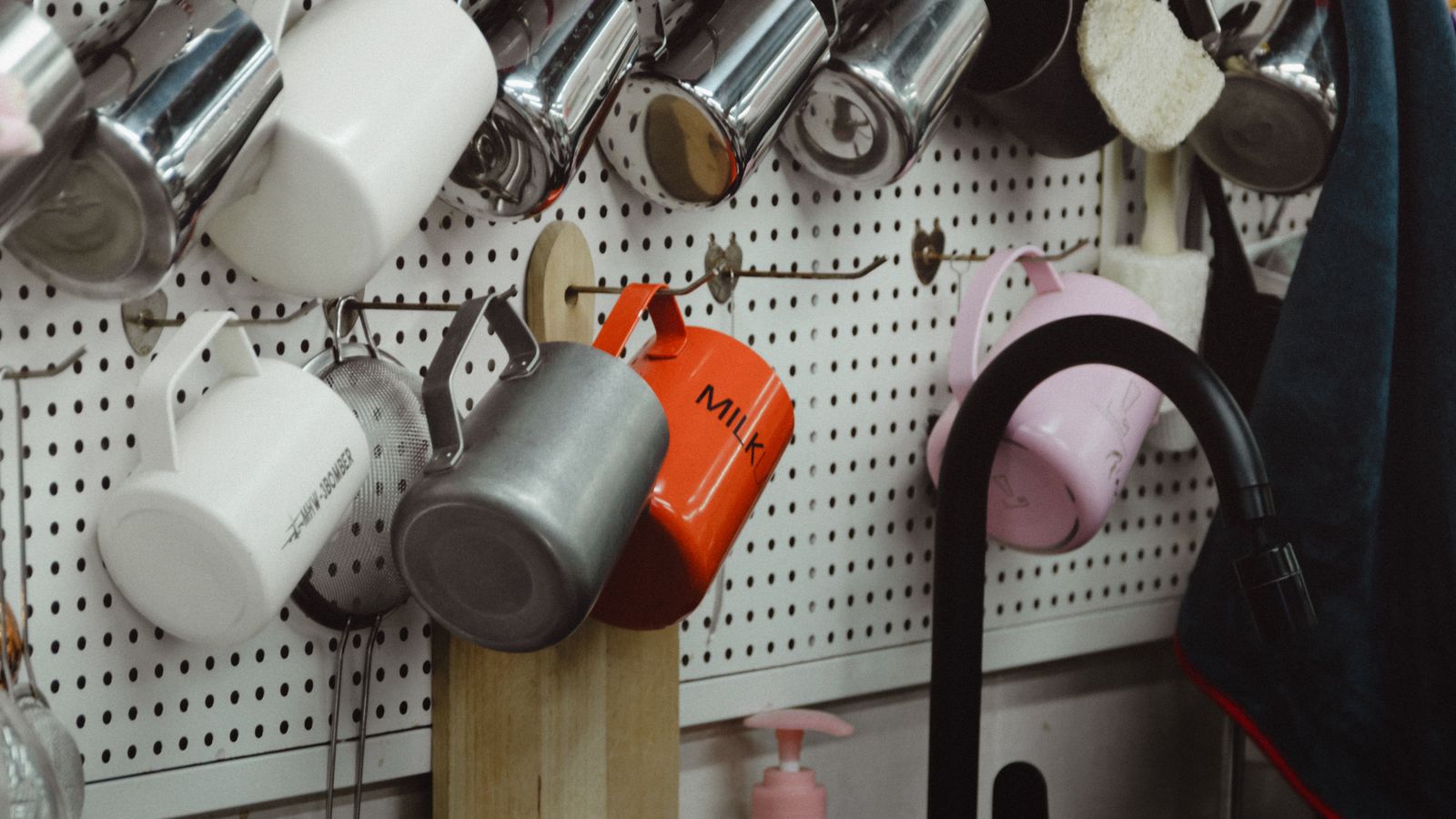 Organized kitchen pegboard holding mugs, utensils, and cookware above a countertop