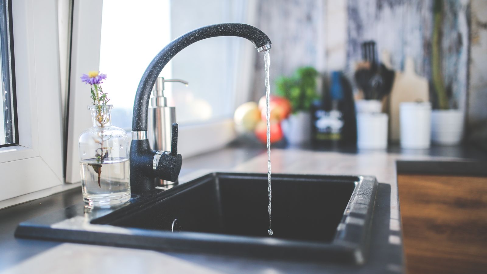 Modern kitchen sink and faucet installed against a tiled backsplash wall