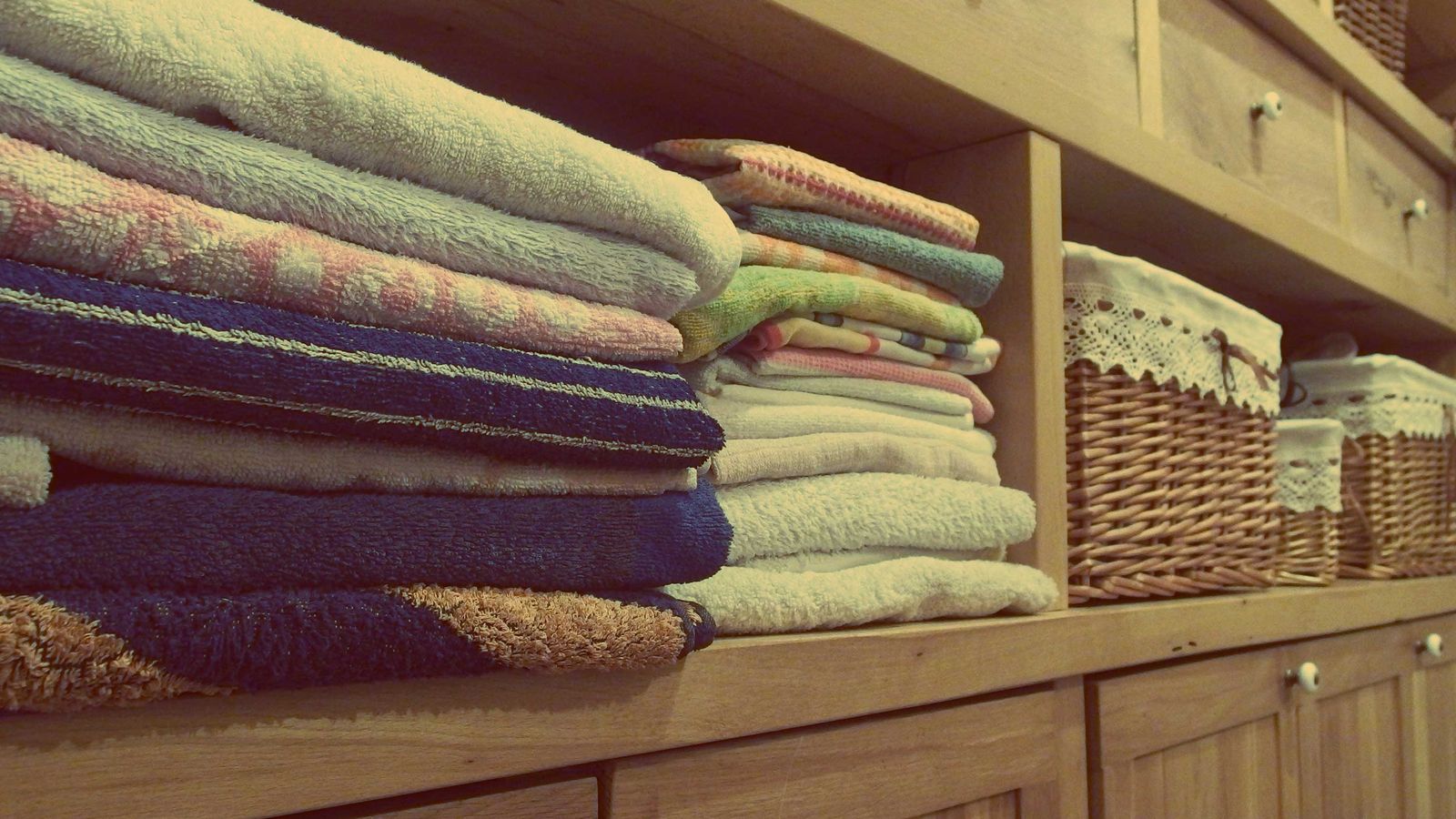 Neatly folded towels stacked on a wooden laundry room shelf