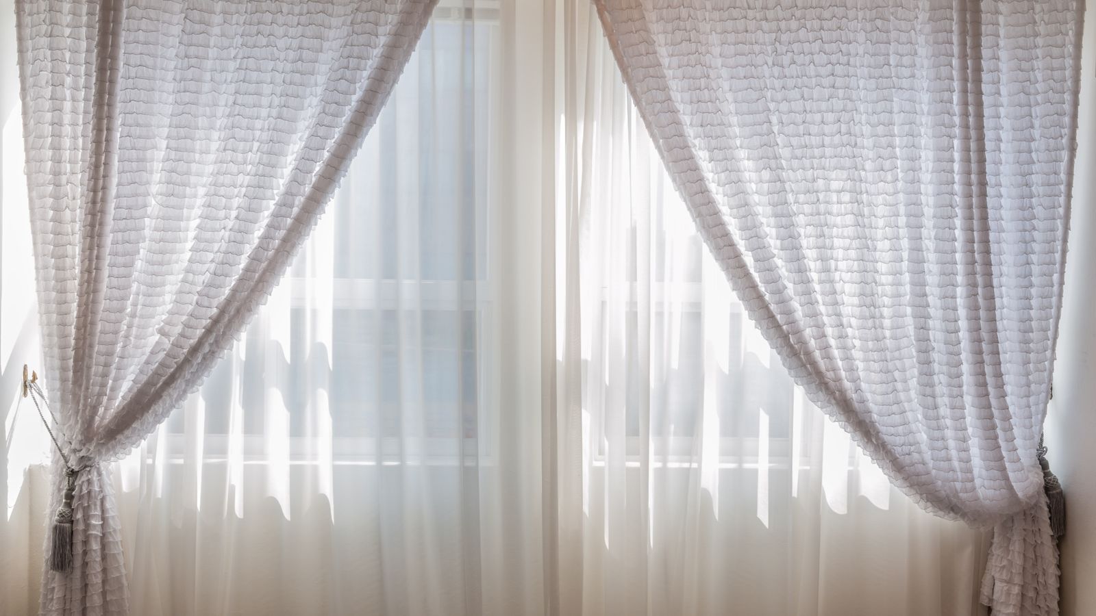 Sheer white curtain panels filtering soft daylight into a living room