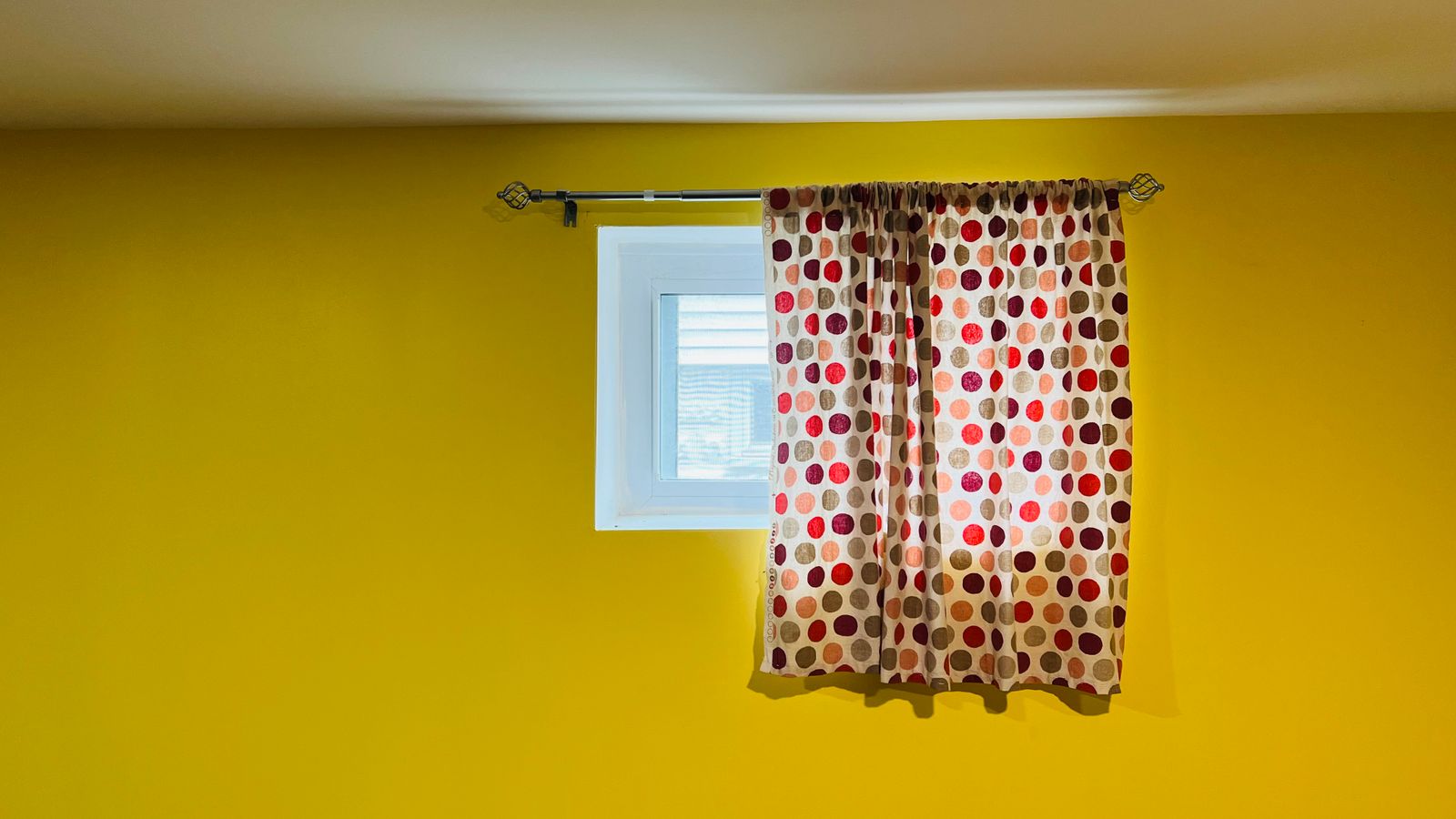 Tension curtain rod mounted inside a window frame holding a light curtain panel