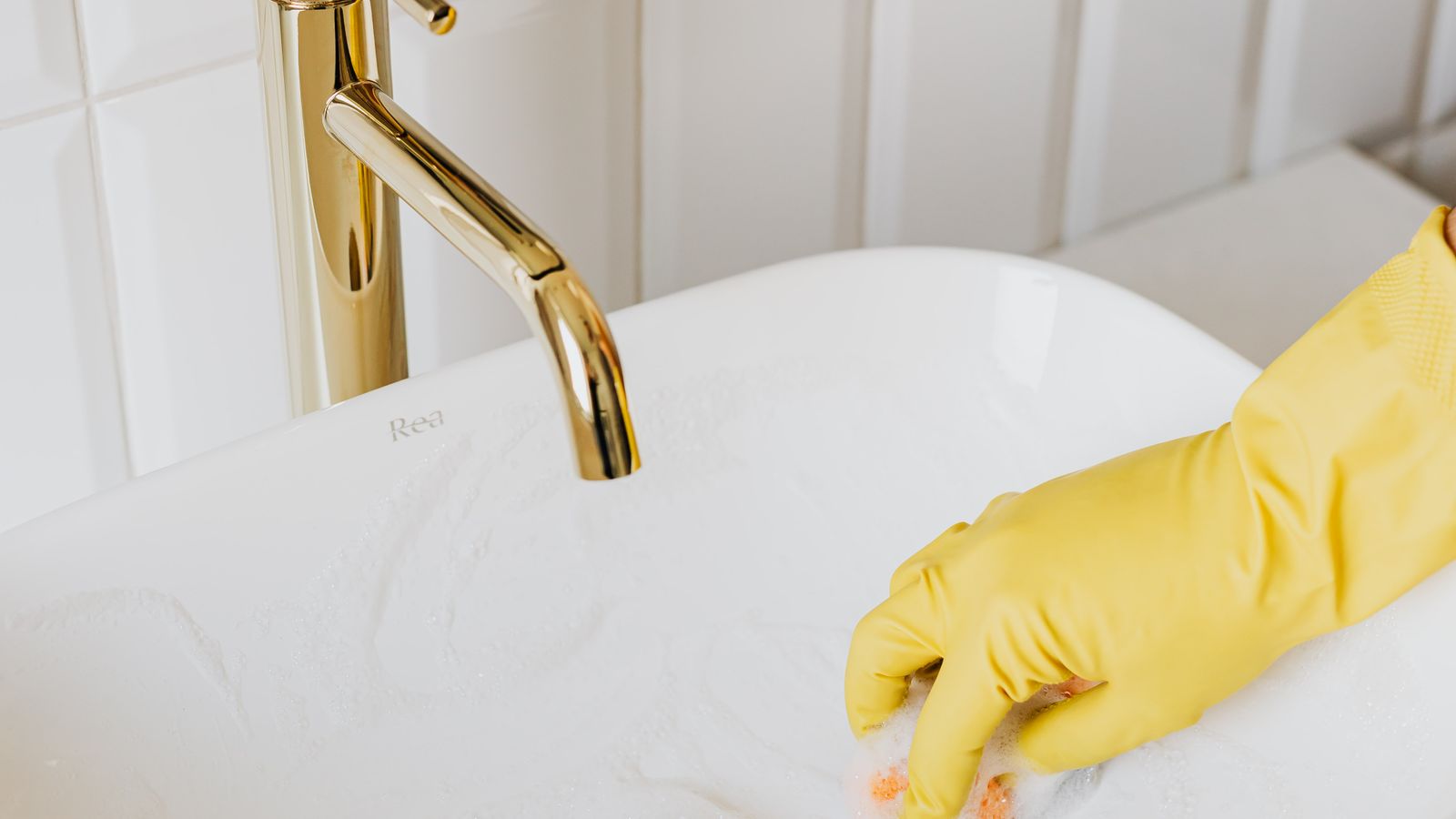Person spraying mildew cleaner on bathroom tile grout