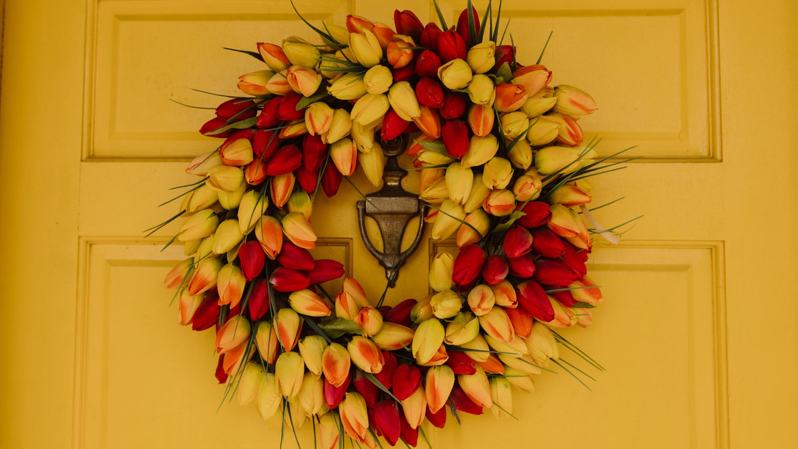 Faux flower stems arranged near a wreath as part of a budget-friendly home decor scheme