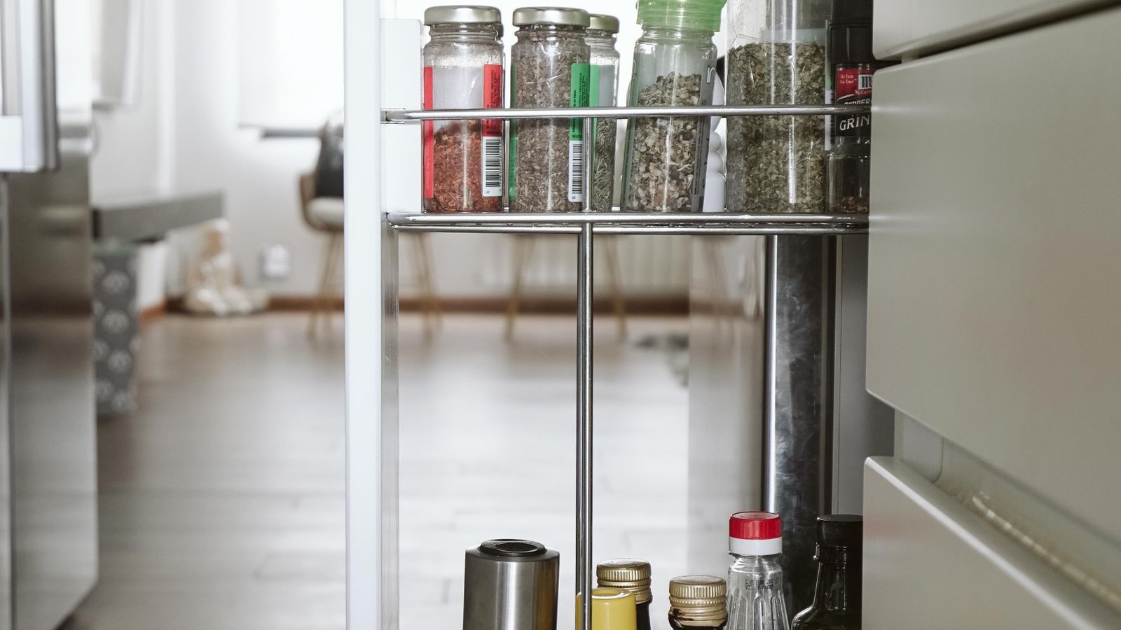 Pull out spice drawer installed in a kitchen cabinet showing organized spice jars