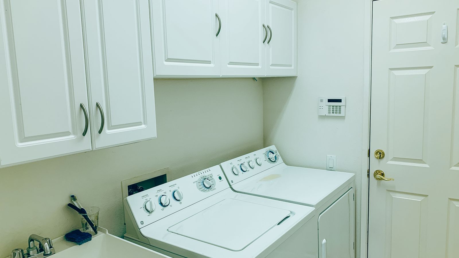 Organized laundry room with white cabinets and folded towels on open shelving
