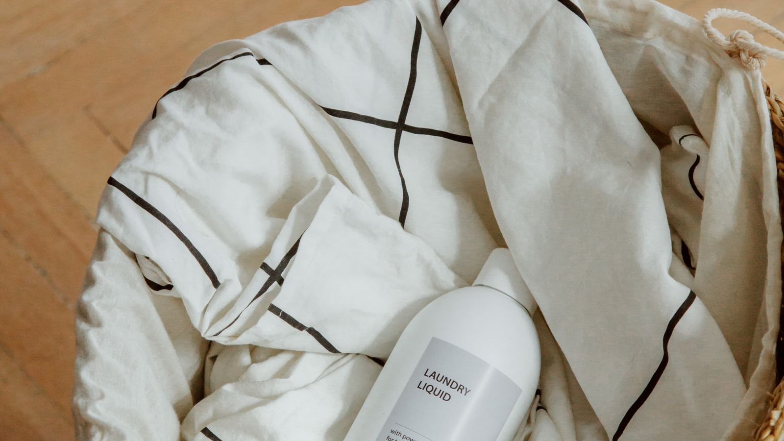 Gentle liquid laundry detergent bottle sitting in a woven laundry basket